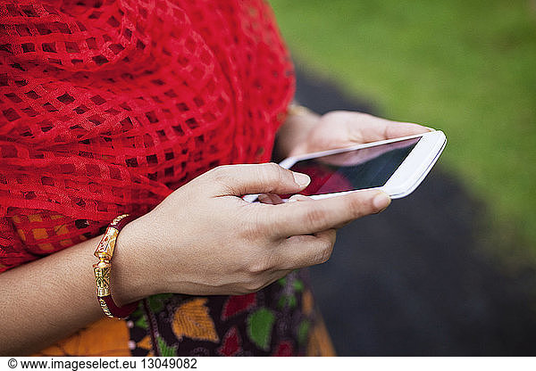 Midsection of woman using smart phone on field
