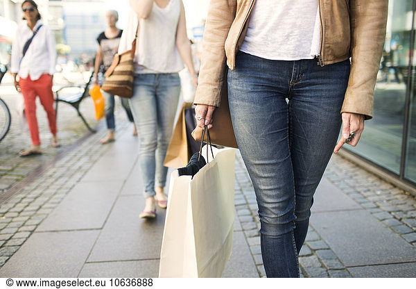 Midsection of woman with shopping bag walking on cobblestone street