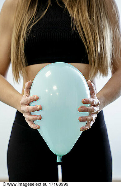 Midwife holding blue balloon against abdomen