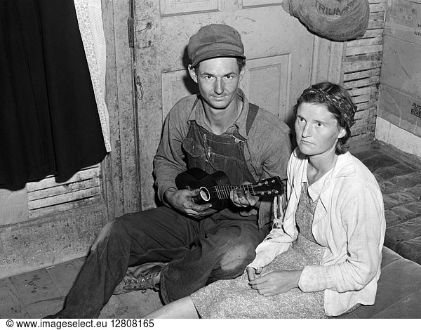 MIGRANT COUPLE  1940. Cherry pickers and parents of five children seated on the floor  Berrien County  Michigan. Photograph by John Vachon in July 1940.