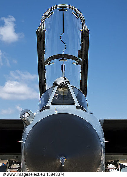 Military fighter jet with open canopy against blue sky