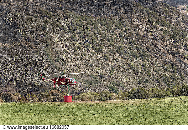 Military helicopter with fire retardant against mountain