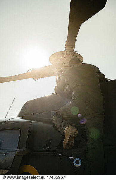military man cleaning a helicopter against sunlight