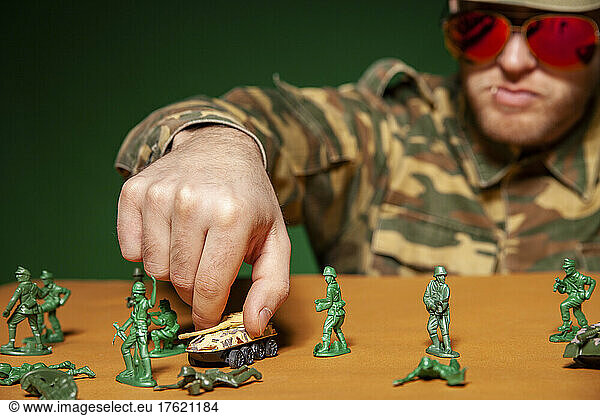 Military soldier arranging armored tank on table