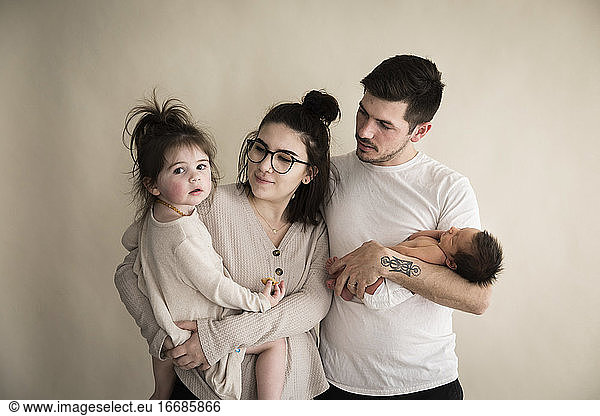 Millenial Hipster Family With Newborn and Toddler With Cream Backdrop