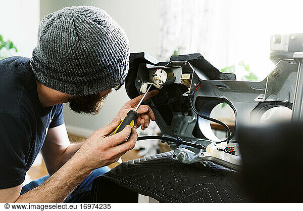 Millennial-Mann restauriert ein Armaturenbrett eines alten Oldtimers im Wohnzimmer