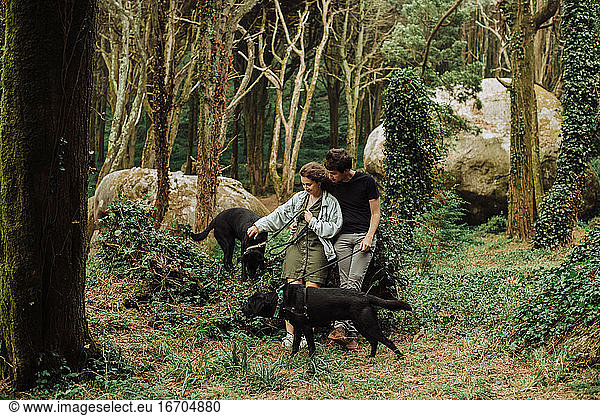 Millennial Mann und Frau mit Hunden an der Leine in der natürlichen Park