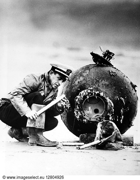 MINE DISPOSAL  1947. Lieutenant D.F. Winslow of the U.S. Navy examines the detonator on a Japanese sea mine that had floated ashore near Newport  Oregon  12 December 1947  more than two years after the end of World War II.