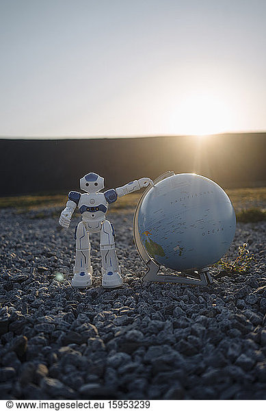 Mini robot with globe on a disused mine tip at sunset