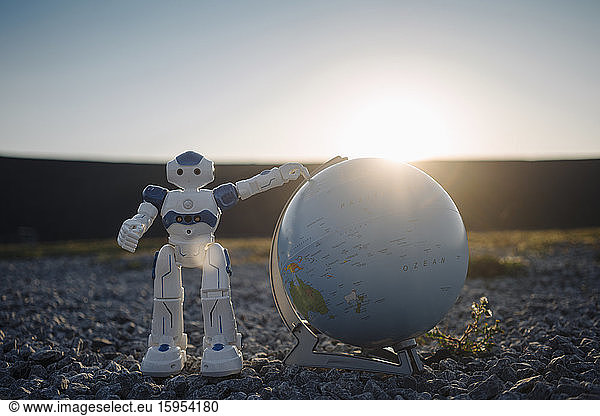 Mini robot with globe on a disused mine tip at sunset