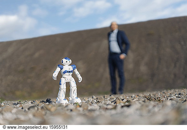 Miniature robot and businessman on a disused mine tip