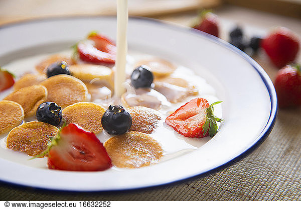 Minipancakes cereal in a bowl with milk and fruit