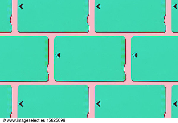 Mint green contactless credit cards pattern on pastel pink background