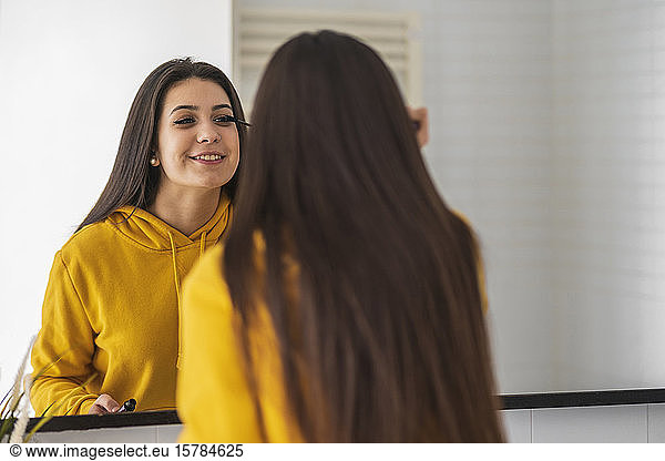 Mirror image of teenage girl applying mascara