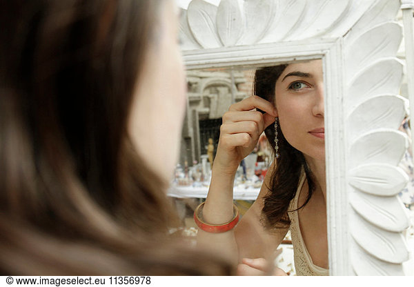 Mirror image of woman trying on earrings at market stall