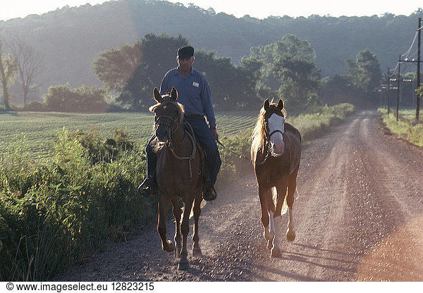 MISSOURI: FARMER & HORSES. A farmer riding one horse and leading another on a dirt road in Louisiana  Missouri (Pike County). Photographed c1974.