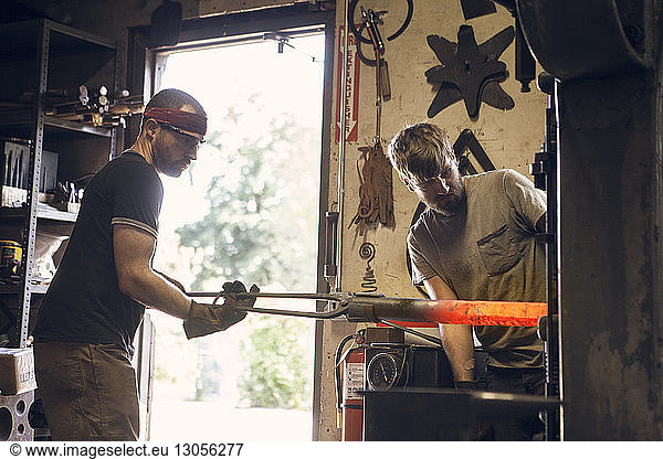 Mitarbeiter formen Stab im Ofen in der Werkstatt