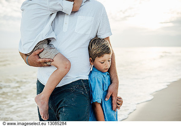 Mitsektion eines Vaters mit Söhnen am Strand von Panama City