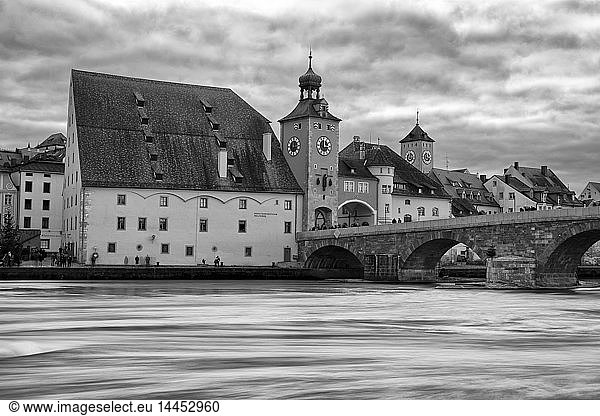 Mittelalterliche Steinbogenbrücke über die Donau mit historischen Gebäuden und Stadttor  Regensburg  Deutschland.