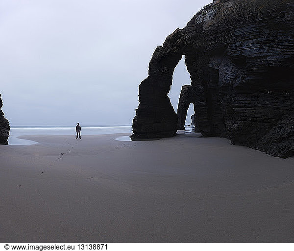 Mitteldistanzansicht eines Mannes  der an einem Felsbogen am Cathedral Beach gegen den Himmel steht