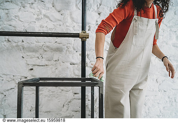 Mittelgroße erwachsene Frau  die in ihrem neuen Laden mit gesenktem Hals am Polierstand steht