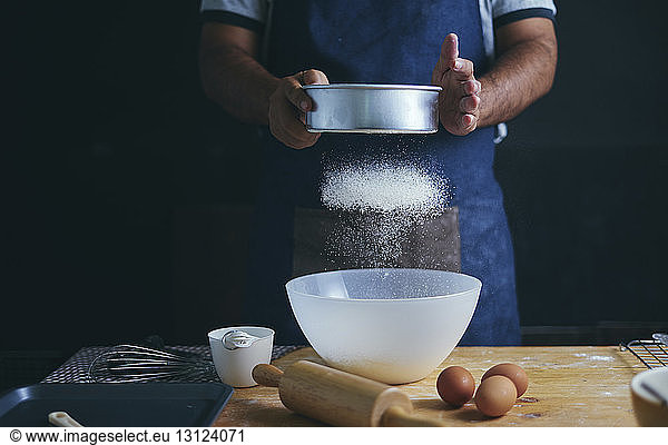 Mittelsektion eines Mannes  der stehend in einer Bäckerei Essen zubereitet