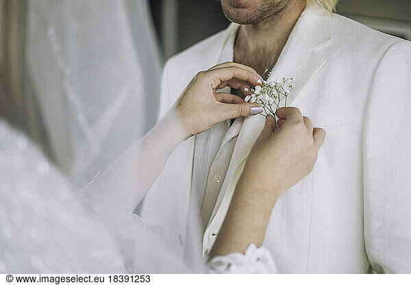 Mittelteil der Braut bei der Anpassung der Boutonniere in der Tasche des Bräutigams bei der Hochzeit