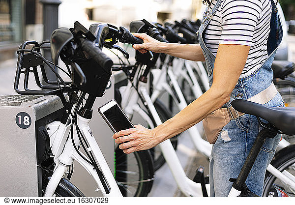 Mittelteil einer Frau  die einen QR-Code an einer Fahrradparkstation scannt