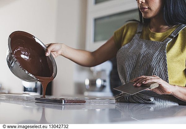 Mittelteil einer Frau  die Schokoladensauce in eine Form gießt
