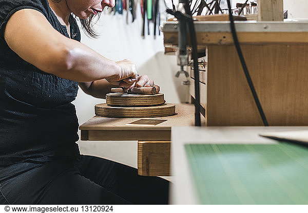 Mittendrin Schmuck herstellende Handwerkerin auf Holztisch in der Werkstatt