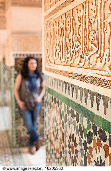 Mittlere erwachsene Frau  an eine geflieste Wand gelehnt  Fokus auf den Vordergrund  Marrakesch  Marokko
