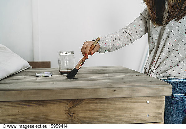 Mittlere erwachsene Frau  die einen Holztisch in ihrem neuen Geschäft lackiert  mittlerer Abschnitt
