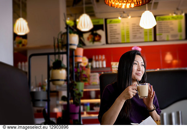 Mittlere erwachsene Frau hält Kaffeetasse im Café