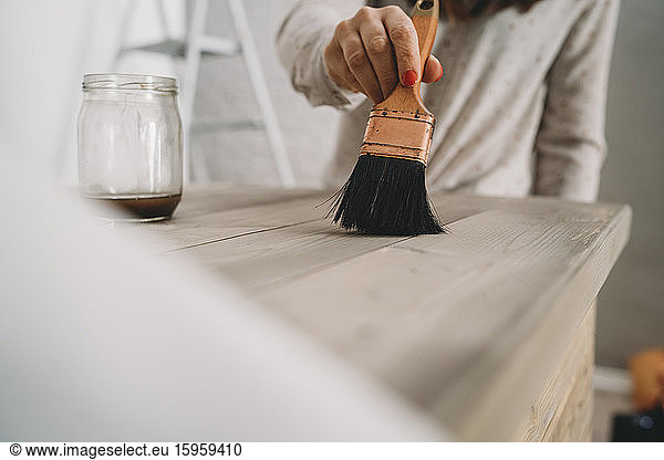 Mittlere erwachsene Frau lackiert einen Holztisch in ihrem neuen Geschäft  geschnittene Ansicht der Oberfläche