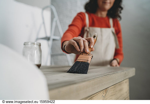 Mittlere erwachsene Frau lackiert Holztisch in ihrem neuen Geschäft  abgeschnittener flacher Fokus
