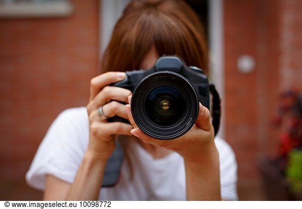 Mittlere erwachsene Frau mit Digitalkamera  Gesicht verdeckt