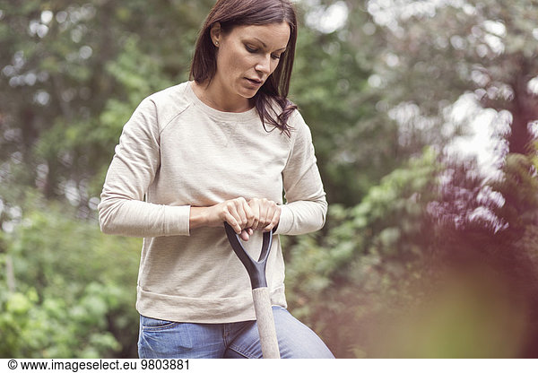 Mittlere erwachsene Frau mit Gartengabel auf Bio-Bauernhof