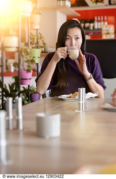 Mittlere erwachsene Frau trinkt Kaffee im Café