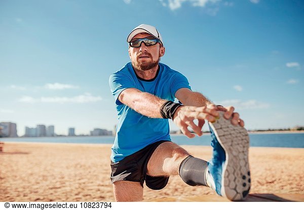 Mittlerer Erwachsener Mann am Strand Bein angehoben  Zehen streckend  Dubai  Vereinigte Arabische Emirate