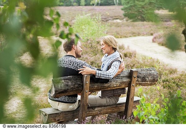 Mittleres erwachsenes Paar auf Holzbank
