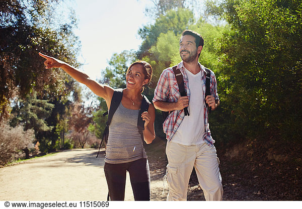 Mittleres erwachsenes Paar beim Wandern  von der sonnenbeschienenen Landstraße aus zeigend