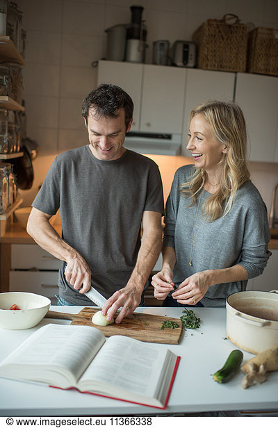 Mittleres erwachsenes Paar beim Zwiebelschneiden in der Küche