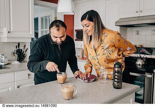 Mittleres erwachsenes Paar  das auf Kaffee auf der Küchentheke zeigt