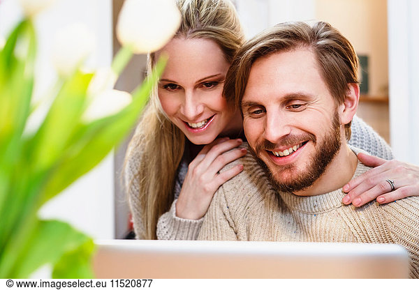 Mittleres erwachsenes Paar  das gemeinsam in der Küche auf den Laptop schaut