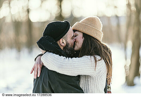 Mittleres erwachsenes Paar in warmer Kleidung  das sich im Wald küsst