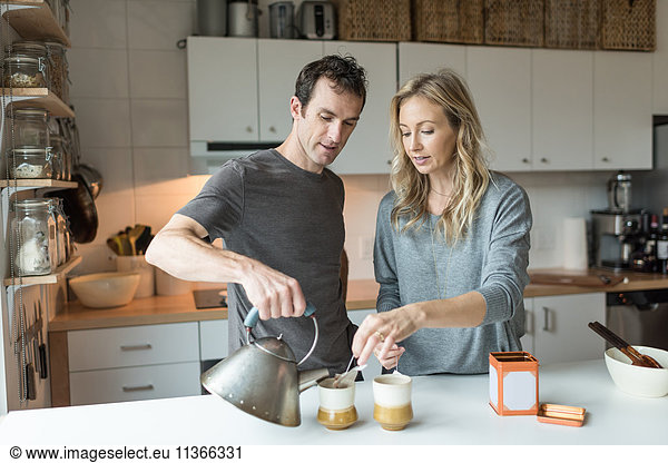 Mittleres erwachsenes Paar macht eine Tasse Tee in der Küche