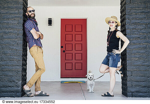Mittleres erwachsenes Paar und Maltipoo-Hund vor einem Haus stehend