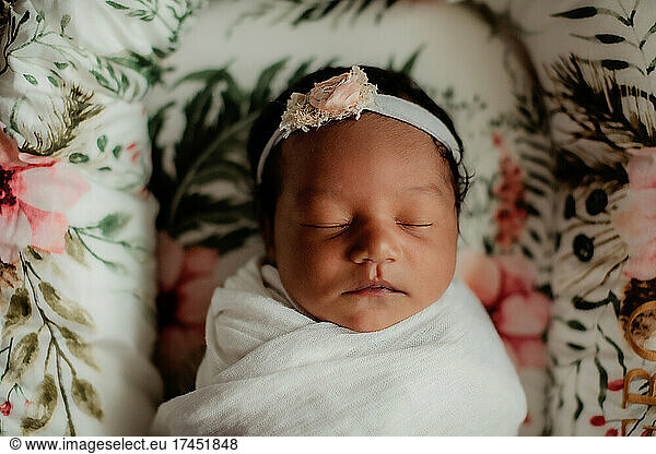 Mixed baby girl sleeping on a tropical print bed