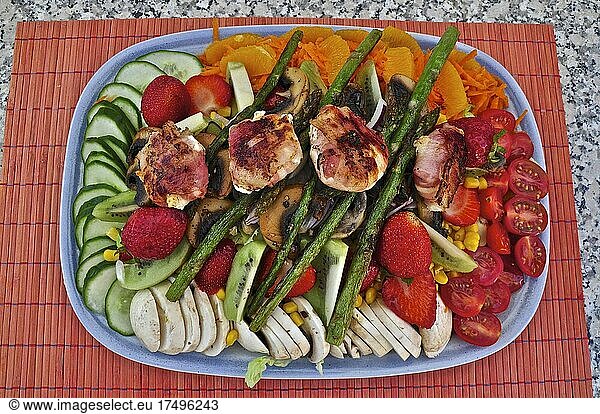 Mixed platter with salad  green asparagus  cucumber  mushrooms  strawberries  carrots and roasted chicken breast