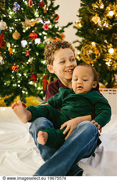Mixed race brothers together smiling in front of Christmas tree